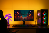Gaming setup with monitor, keyboard, and RGB-lit computer tower on a desk.